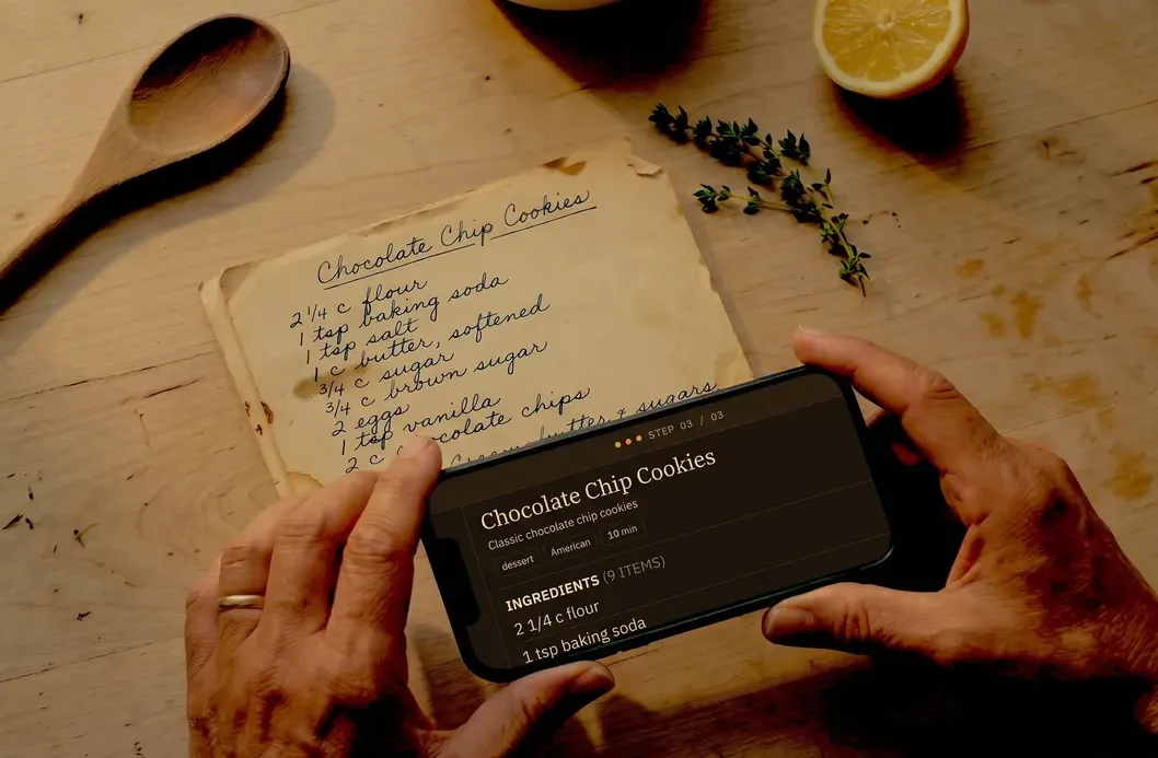 Hands holding a phone over a handwritten family recipe card.